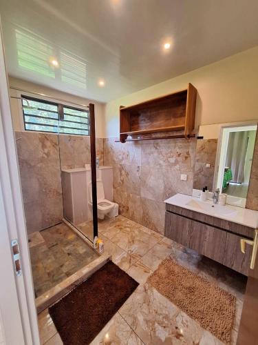 a bathroom with a shower and a toilet and a sink at Temoe'ani House in Uturoa