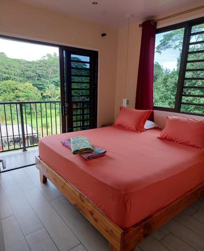a bedroom with a large red bed with a balcony at Temoe'ani House in Uturoa