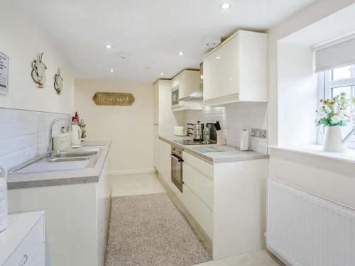 a white kitchen with white cabinets and a sink at Wagtail Cottage-Ukc6984 in Castleside