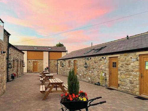 a patio with wooden benches and tables with a sunset at Wagtail Cottage-Ukc6984 in Castleside