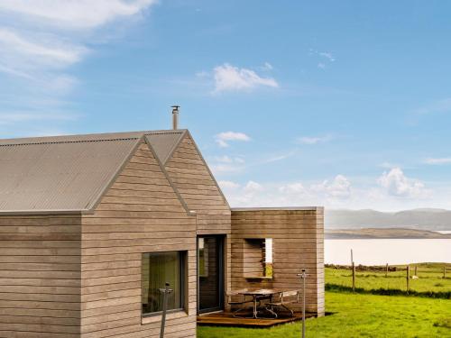 a small wooden house with a table in front of a field at The Two Byres in Trumpan