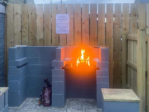 a brick fire pit in front of a wooden fence at Swallow Cottage-Ukc6983 in Castleside