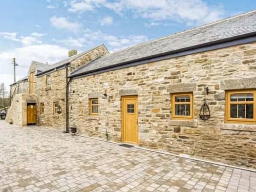 a stone building with yellow doors and a cobblestone street at Barn Owl Cottage- Ukc6985 in Castleside