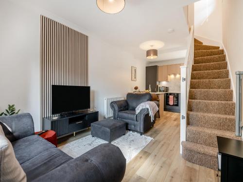 a living room with a couch and a tv and stairs at Star Cottage in Ringwood