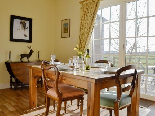 a dining room with a wooden table and chairs at Osprey Cottage - Uzq in Kirkton of Airlie