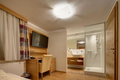 Hotel Leimer Bräu في Lenzing: غرفة نوم بسرير ودش وتلفزيون
