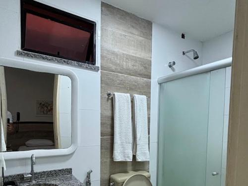 a bathroom with a mirror and a tv on the wall at Tropical Praia Hotel in Aracaju