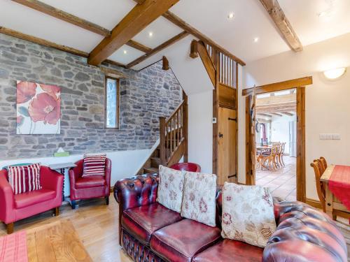 a living room with red furniture and a stone wall at Wern Farm Barn in Cwm-du