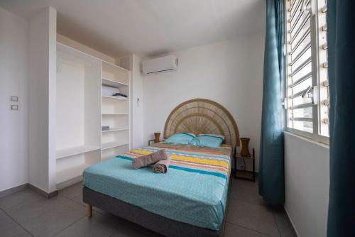 a bedroom with a bed in a room with a window at Appartement bois de chaumes in Cayenne