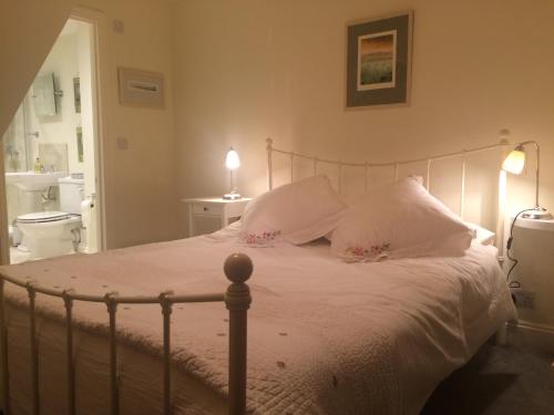 a bedroom with a bed with white sheets and pillows at Old Station Gardens, SW London in Teddington