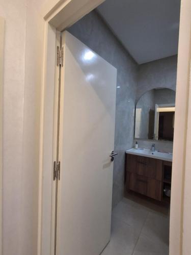a bathroom with a white door and a sink at Appartement Residence Tafoult IMIOUADDAR in Agadir nʼ Aït Sa