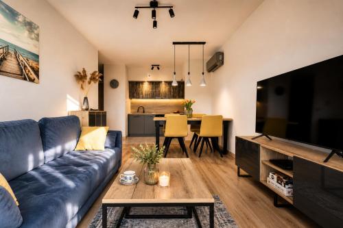 a living room with a blue couch and a television at Sea View & SPA 10d10 in Dziwnów