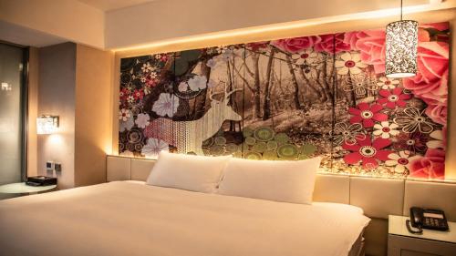 a bedroom with a bed and a painting on the wall at The Cloud Hotel in Kaohsiung