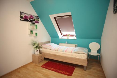 a small bedroom with a bed with a blue wall at Ferienhaus Victoria in Norden