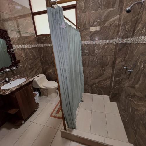 a bathroom with a shower and a toilet and a sink at Núba Hospedaje in Baños
