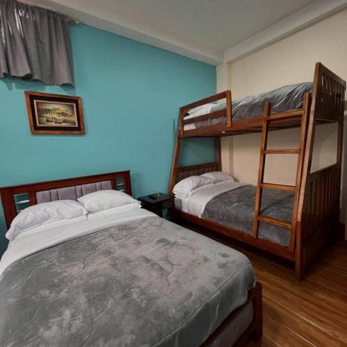 a bedroom with two bunk beds and a blue wall at Núba Hospedaje in Baños