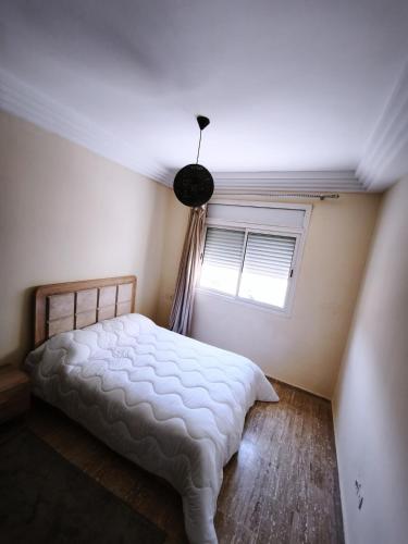 a bedroom with a white bed and a window at Cozy Beach Apartment Diar Mansour Rabat in Rabat