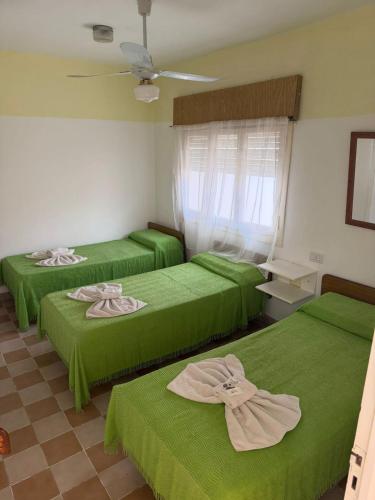 three beds in a room with green sheets at Malibu in Termas de Río Hondo