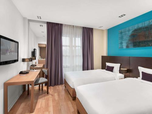 a hotel room with two beds and a desk at Mercure Hanoi La Gare Hotel in Hanoi