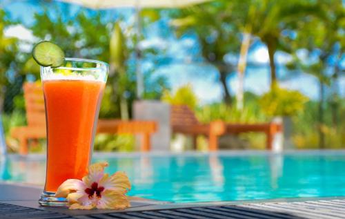 a drink sitting on a table next to a swimming pool at Wild Le Green in Udawalawe