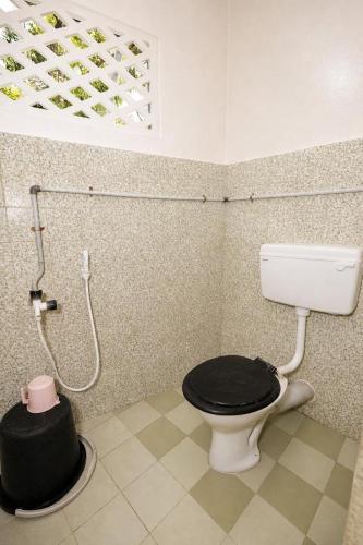 a bathroom with a toilet with a black seat at Noble Darshan in Guruvāyūr