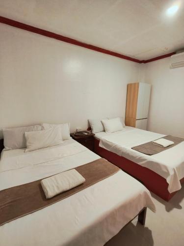 two beds in a room with white walls at Tugbongan North Siargao in Burgos