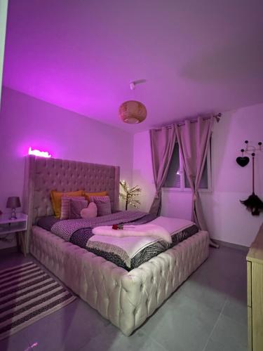 a bedroom with a large bed with purple lighting at Suite Jacuzzi Giverny Paris in Freneuse