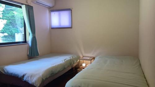two beds in a room with a window at 民泊kururu 個室 鍵付き朝パン付きライダー用ガレージ有り in Nishidani
