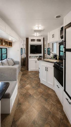 a kitchen with white cabinets and a couch in a caravan at 2-bedroom Camper Trailer Cottage #3 in Dillon