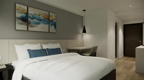 a bedroom with a large white bed with blue pillows at Skyview Apartment by Grand Sky Hotel in Sunggal