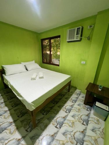 a green bedroom with a large bed with a window at Jaliha Homestay in San Isidro