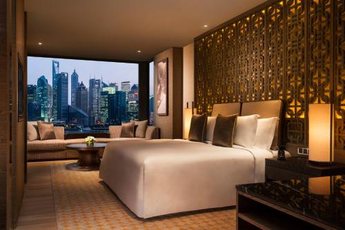 1 dormitorio con 1 cama grande y vistas a la ciudad en Banyan Tree Shanghai On The Bund en Shanghái