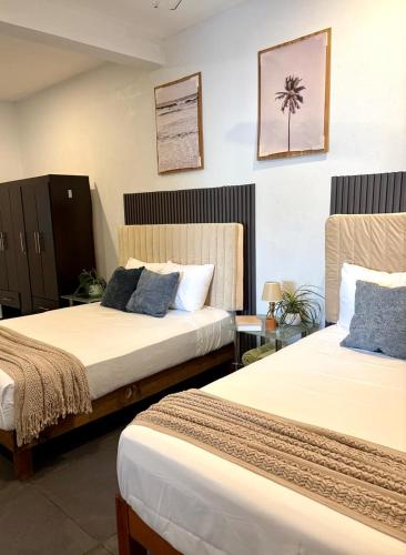 a hotel room with two beds and a palm tree on the wall at Casa Alma de Mar in Brisas de Zicatela