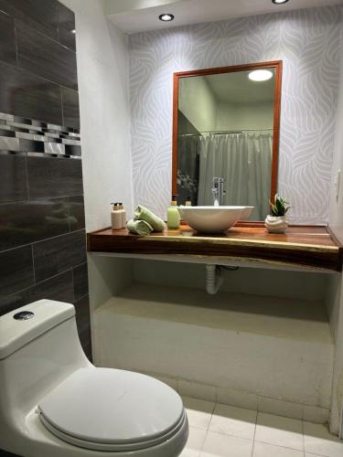 a bathroom with a sink and a toilet and a mirror at Casa Alma de Mar in Brisas de Zicatela
