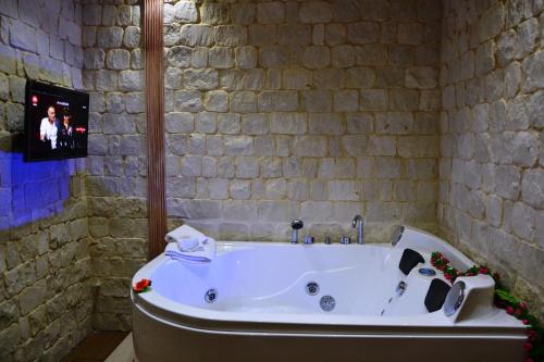 a bath tub in a bathroom with a stone wall at Casa Aruci Sweet Home in Scicli