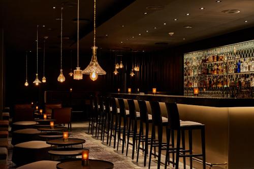 a restaurant with a bar with chairs and lights at Pullman Cologne in Cologne