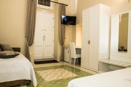a bedroom with two beds and a desk and a tv at Stanze Orsini in Gravina in Puglia