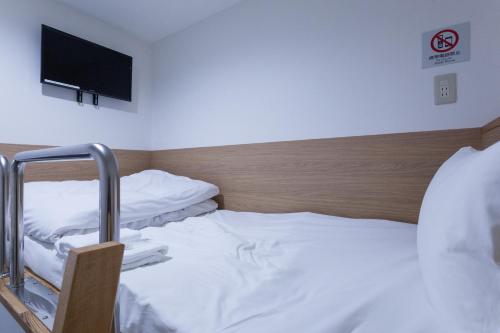 a room with two beds and a flat screen tv at HOTEL THE CUBE Naha Kokusai Street in Naha