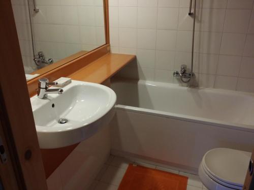a bathroom with a sink and a tub and a toilet at Appartamento Artuik in Marilleva