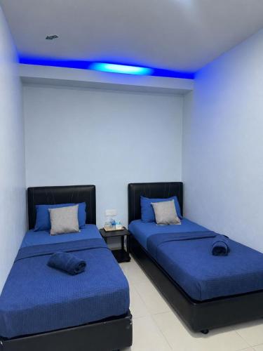 two beds in a room with blue lights on the ceilings at Ilhamku Inn in Kampong Kemaman