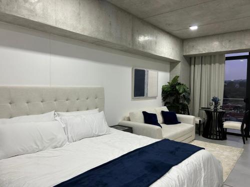 a bedroom with a large white bed and a couch at Estudio 905 in San Salvador
