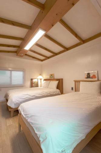 two beds in a room with white sheets at 스테이 모슬 in Daejeong