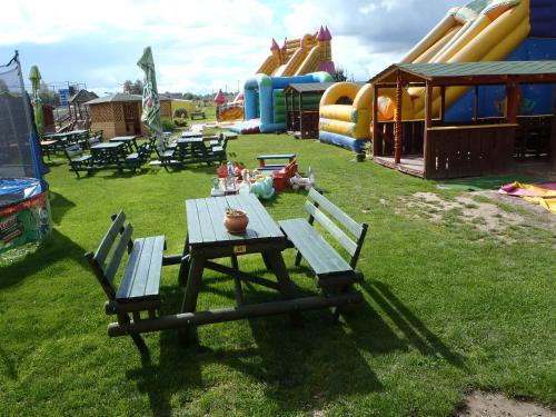 a picnic table and chairs in a park with slides at Geltona in Šiauliai