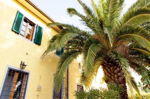 a palm tree in front of a yellow building at Agriturismo Podere Rondinaio in Lamporecchio