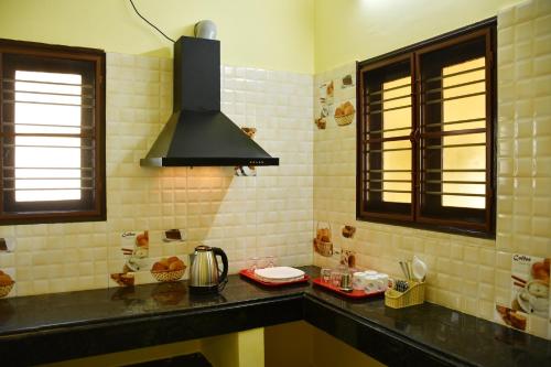 a kitchen with a black counter top and two windows at Srinivasam service apartment in Madurai