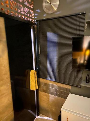 a bathroom with a shower with a window and a television at BACKHOUSE Vieiralves - Manaus in Manaus