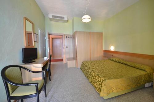 um quarto com uma cama, uma secretária e uma televisão em Hotel Stella Maris em Capoliveri