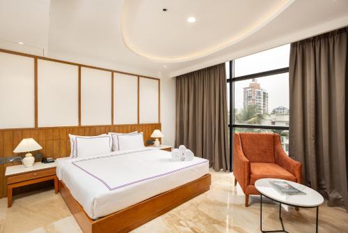 a bedroom with a large bed and a chair at Hotel Explora Calicut by Nova in Kozhikode