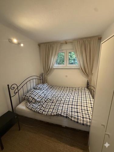 a bedroom with a bed with a checkered blanket and a window at Domek letniskowy Wielonek 4 in Cierplewo