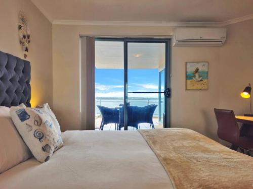 a bedroom with a bed and a view of the ocean at Toukley Waterfront Apartment with Balcony - Outdoor Pool - Secure Parking - Wi-Fi - By HappyHosts in Toukley